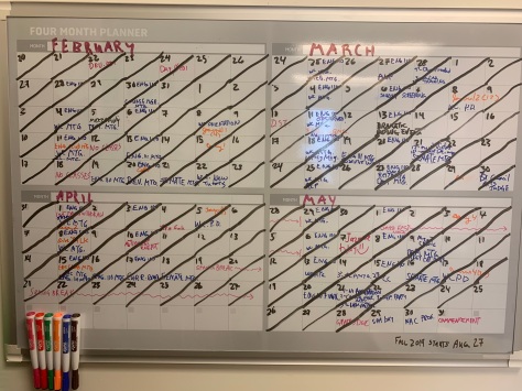 Photo of the 4-month calendar—February through May—on the wall of my office. All the dates are crossed out. You can make out all daily events.